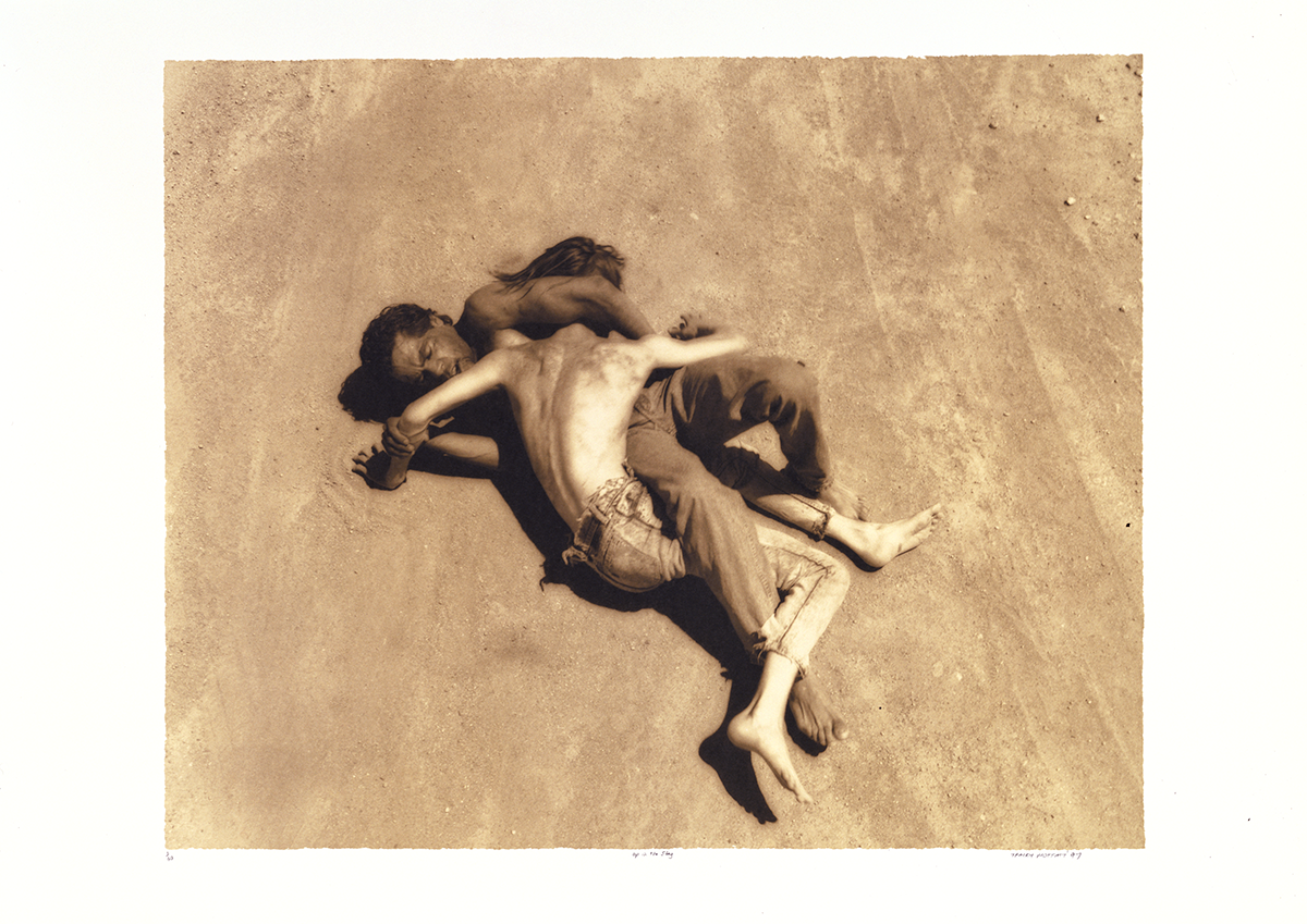 Sepia photograph of two male youths wrestling on bare earth.