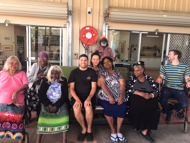 Iltja Ntjarra artists at their studio with Tony Albert. Front row, from left: Noreen Hudson, Ivy Pareroultja, Tony Albert, Vanessa Inkamala, Kathleen France and Harry Copas (Albert’s assistant). Middle row: Gloria Pannka and Koren Wheatley (coordinator). Rear: Mervyn Rubuntja