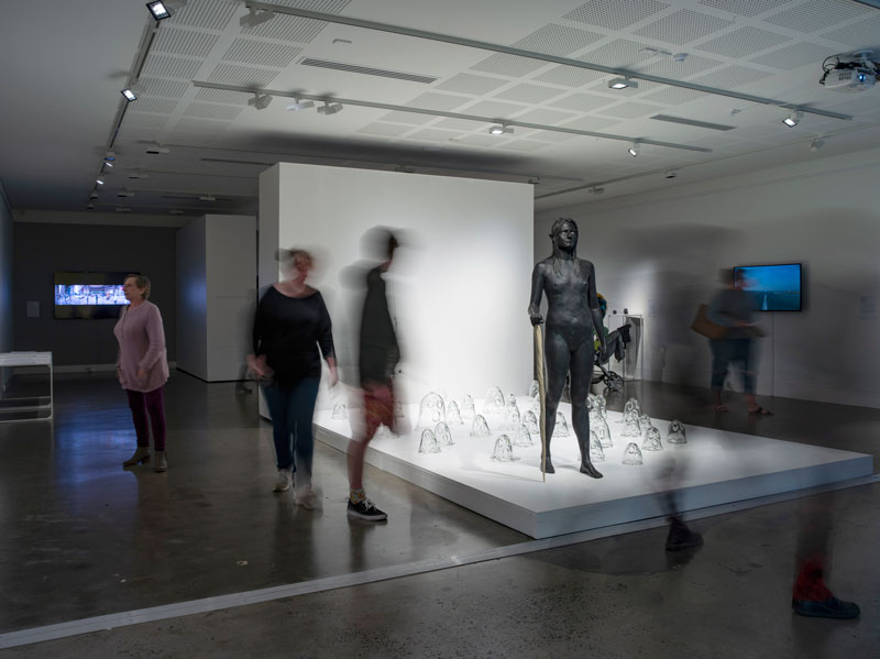 Nell, A white bird flies in the mist, a black bird flies in the night, a woman walks, wild and free, she is not afraid to die, bronze, mother of pearl, resin, 33 individually hand-blown clear glass ghost sculptures, 2008. Instillation view, Lismore Regional Gallery. Photo: Carl Warner