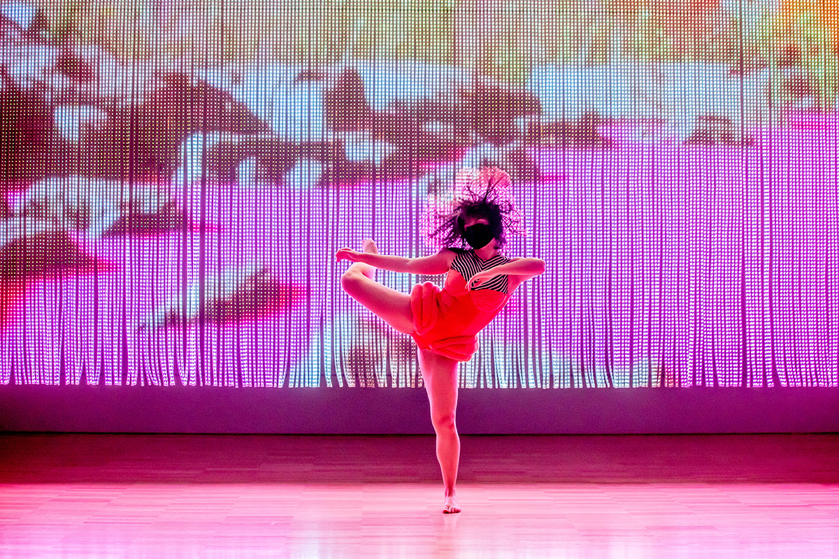 Dancer performing in front of a pink screen with image of rocks