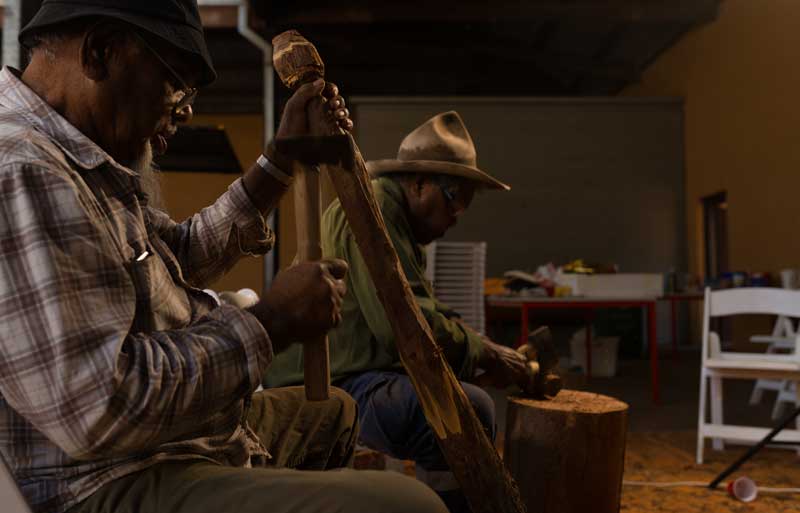 Roy Coulthard and Philip Naylor carving at Yarta Purtli Barracks, Port Augusta. Photo: Dave Laslett, courtesy of Ku Arts